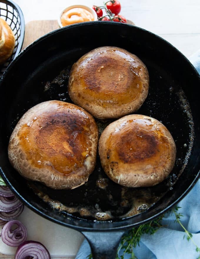 Golden and cooked tops of the mushrooms flipped to the other side to continue cooking 