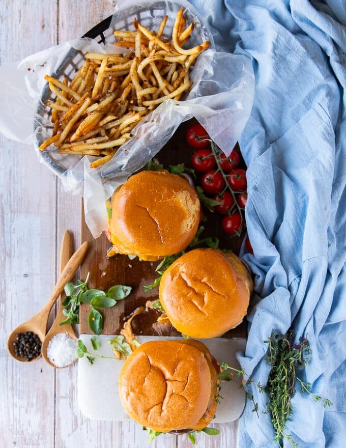 A set of three portobello mushroom burgers on a wooden board ready and assembled with a side of fries 