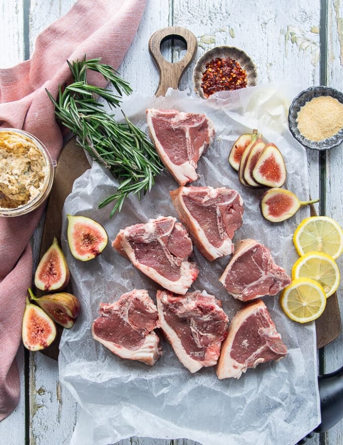 raw and trimmed lamb loin chops on a parchment paper on a wooden table showing the details of the cut of meat
