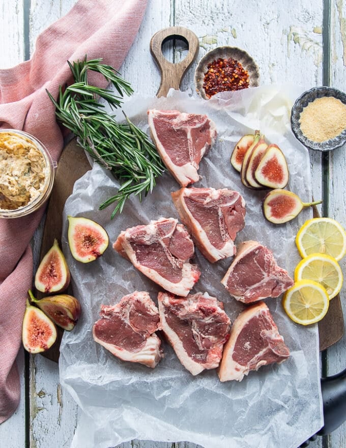raw and trimmed lamb loin chops on a parchment paper on a wooden table showing the details of the cut of meat
