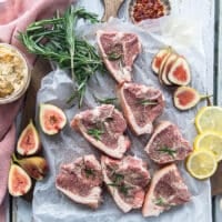 Lamb loin chops on a parchment paper seasoned on both sides with salt, pepper, onion flakes and fresh rosemary