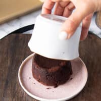 a hand slowly removing the flipped ramekin to show the cake perfectly cooked