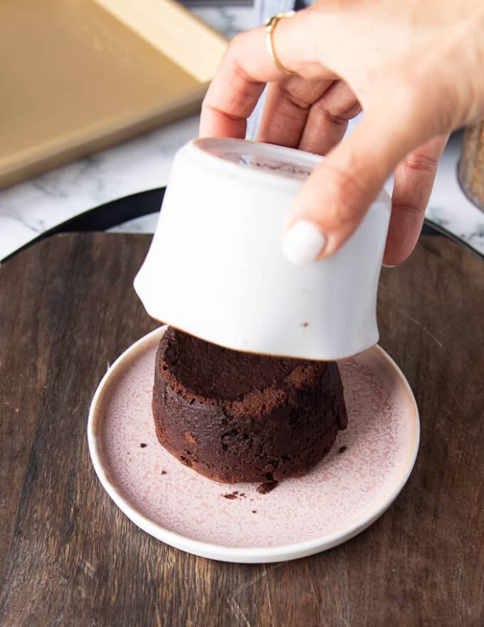 a hand slowly removing the flipped ramekin to show the cake perfectly cooked 