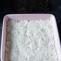 Sushi rice is flattened and spread into a 9 inch square baking pan