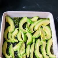 Avocado slices are arranged on top of the seaweed sheet in the baking pan
