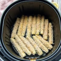 coated zucchini fries in a single layer in an air fryer basket