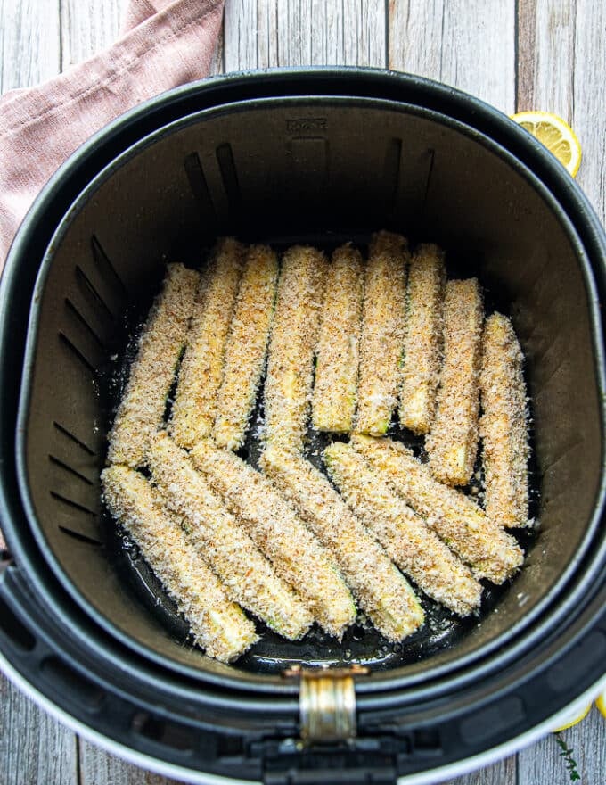 coated zucchini fries in a single layer in an air fryer basket 