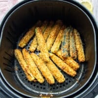 golden and perfect air fryer zucchini fries in the basket of the air fryer
