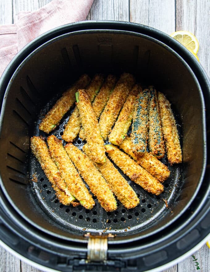 golden and perfect air fryer zucchini fries in the basket of the air fryer 