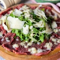 side view of a beef carpaccio showing the layers of beef and dressing