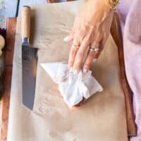 A hand pat drying the piece of beef tenderloin to make sure no moisture is on the surface