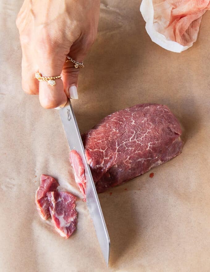 a hand holding a very sharp knife to cut thin slices of the tenderloin