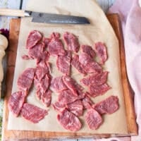 the beef tenderloin sliced in to paper thin slices on a parchment paper lined board