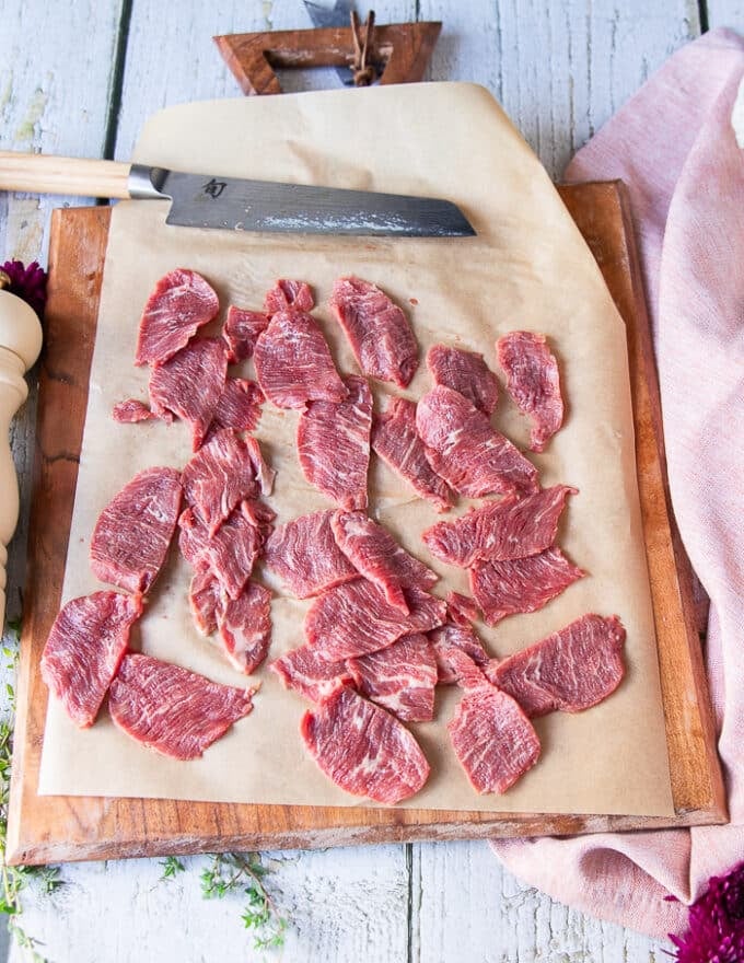 the beef tenderloin sliced in to paper thin slices on a parchment paper lined board