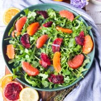 Layering the halloumi salad on a plate with arugula as a base, and some orange segments, blood oranges, and grapefruit