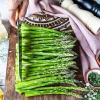 A hand trimming the asparagus using a knife to cut off the tough stems