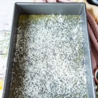 A thin layer of parmesan and herbs are sprinkled on the baking sheet over the melted butter