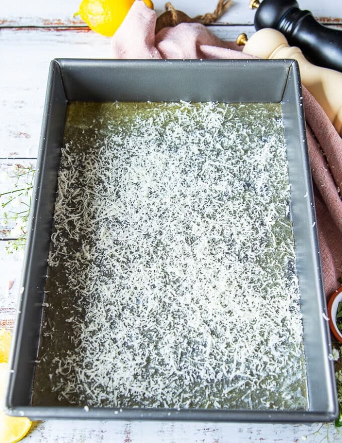 A thin layer of parmesan and herbs are sprinkled on the baking sheet over the melted butter 