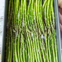 The trimmed asparagus arranged in a single layer over the baking sheet and ready to roast