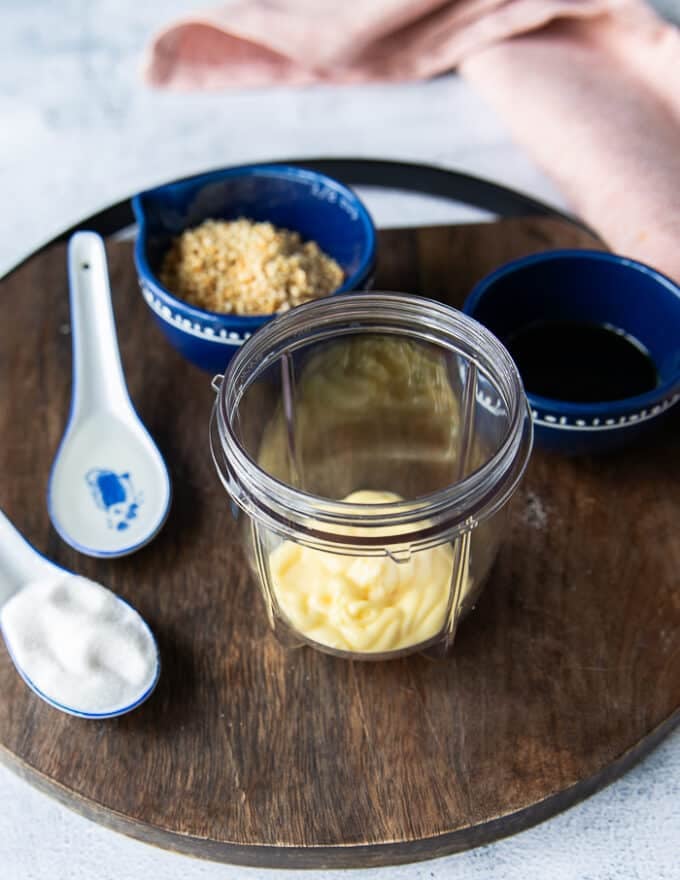 ingredients to make sesame salad dressing including a bowl of toasted sesame, kewpie mayo, soy sauce, salt and suagar