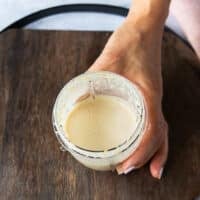 Sesame salad dressing ready in a bowl of a food processor, A hand showing close up of how smooth it is