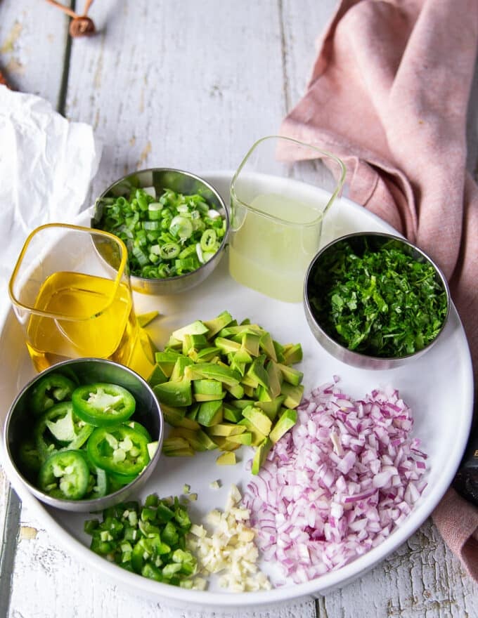 Remaining ingredients to make the tuna ceviche including olive oil, some diced red onions, some diced jalapenos, some cilantro minced, a bowl of lime juice, some avocados diced, 