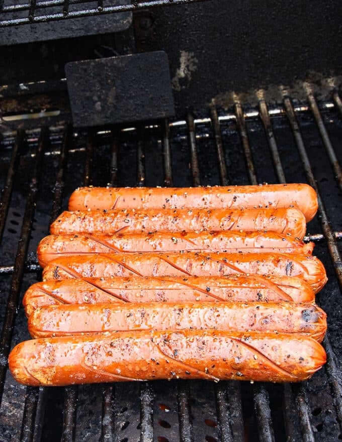 Grilled hot dogs are ready, golden and blistered on the grill and ready to serve