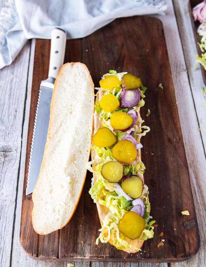 piling up of sandwich ingredients over the bread. Lettice followed by onions, followed by pickles and tomatoes