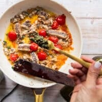 A hand adding in a spoonful of capers to the sauce pan