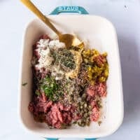 The steak tartare ingredients all added into the beef mixture including onions, capers, mustard, Worcestershire sauce, herbs, salt and pepper