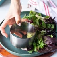 A hand holding a 3 inch round mold to use for shaping the steak tartare