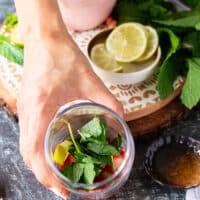 Lots of fresh mint, lime slices and honey is added to the strawberries at the bottom of the cup