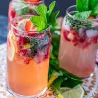Close up on one strawberry mojito showing the crushed strawberries, lime slices and mint and garnished with more berries, mint and lime