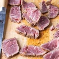a sharp knife slicing the chilled tenderloin steak to make slices of beef tataki