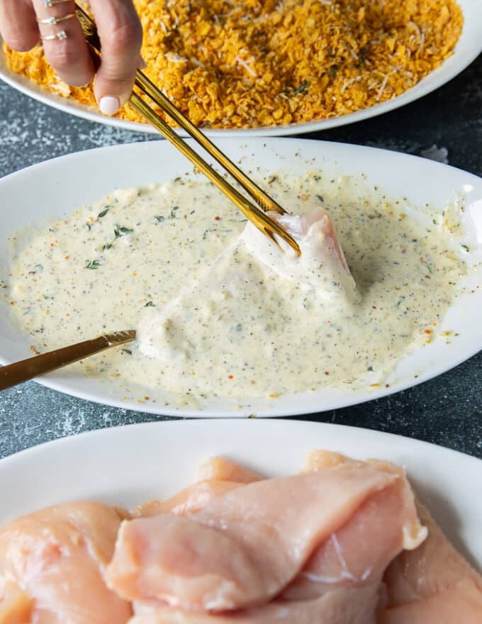 coating process of the hot honey chicken, one chicken tender dipped into the wet bowl 