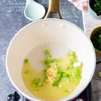 Scallions and garlic sautéing in olive oil in a pot to flavor the base of cilantro lime rice recipe