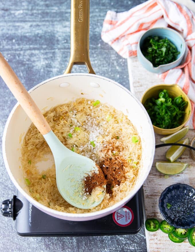 The rice is seasoned with salt and chilli powder in the pot 