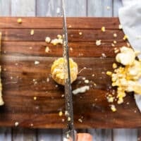 The corn standing up right on the board and a knife used to cut down the half