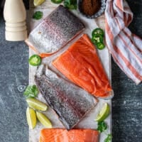 A board with rainbow trout surrounded by salt, pepper and chilli powder, and some oil