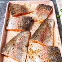 heavily oiled and seasoned rainbow trout fillets on a sheet ready to grill
