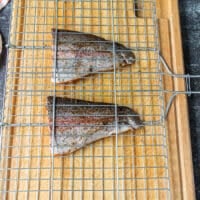 seasoned and oiled trout in the middle of a grill basket ready to grill