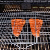 grill basket with trout on the grill over high heat ready to flip