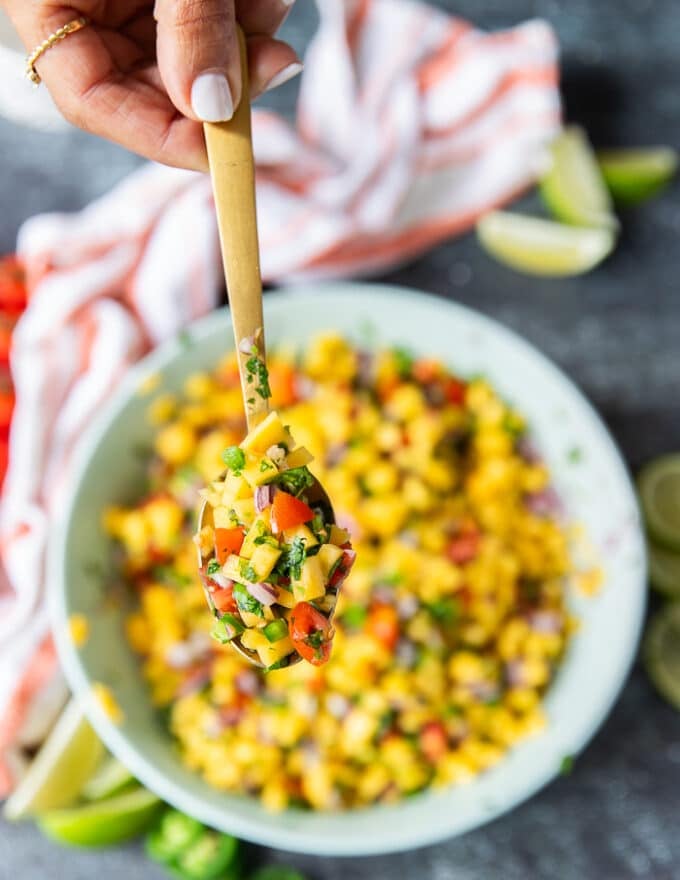 a spoonful of mango pico de gallo close up showing details of the pico