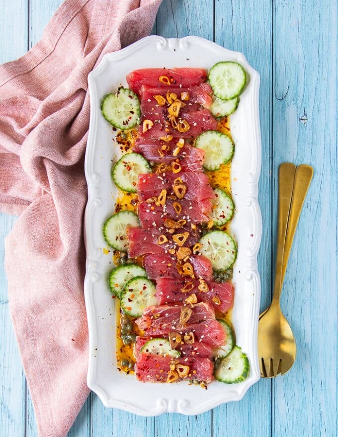 Top view of the finished tuna crudo plate with fresh tuna, cucumbers, garlic chips and the zesty citrus vinaigrette 