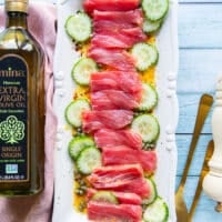 Thinly sliced tuna and cucumbers arranged on a serving plate