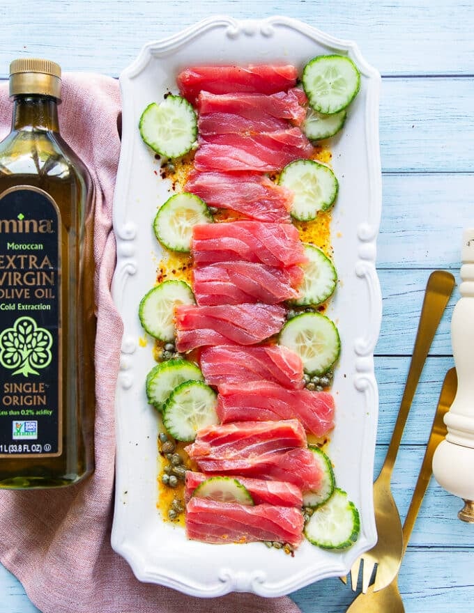 Thinly sliced tuna and cucumbers arranged on a serving plate 