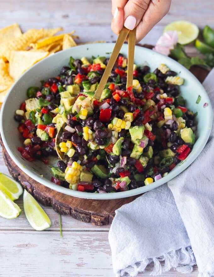 tow spoons scooping up some black bean and corn salad and showing close up of the textures
