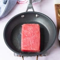The seasoned Tuna placed in a hot skillet with neutral oil