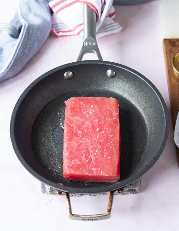 The seasoned Tuna placed in a hot skillet with neutral oil