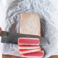 A sharp knife used to slice the tuna showing the beautiful pink raw inside of the ahi tuna